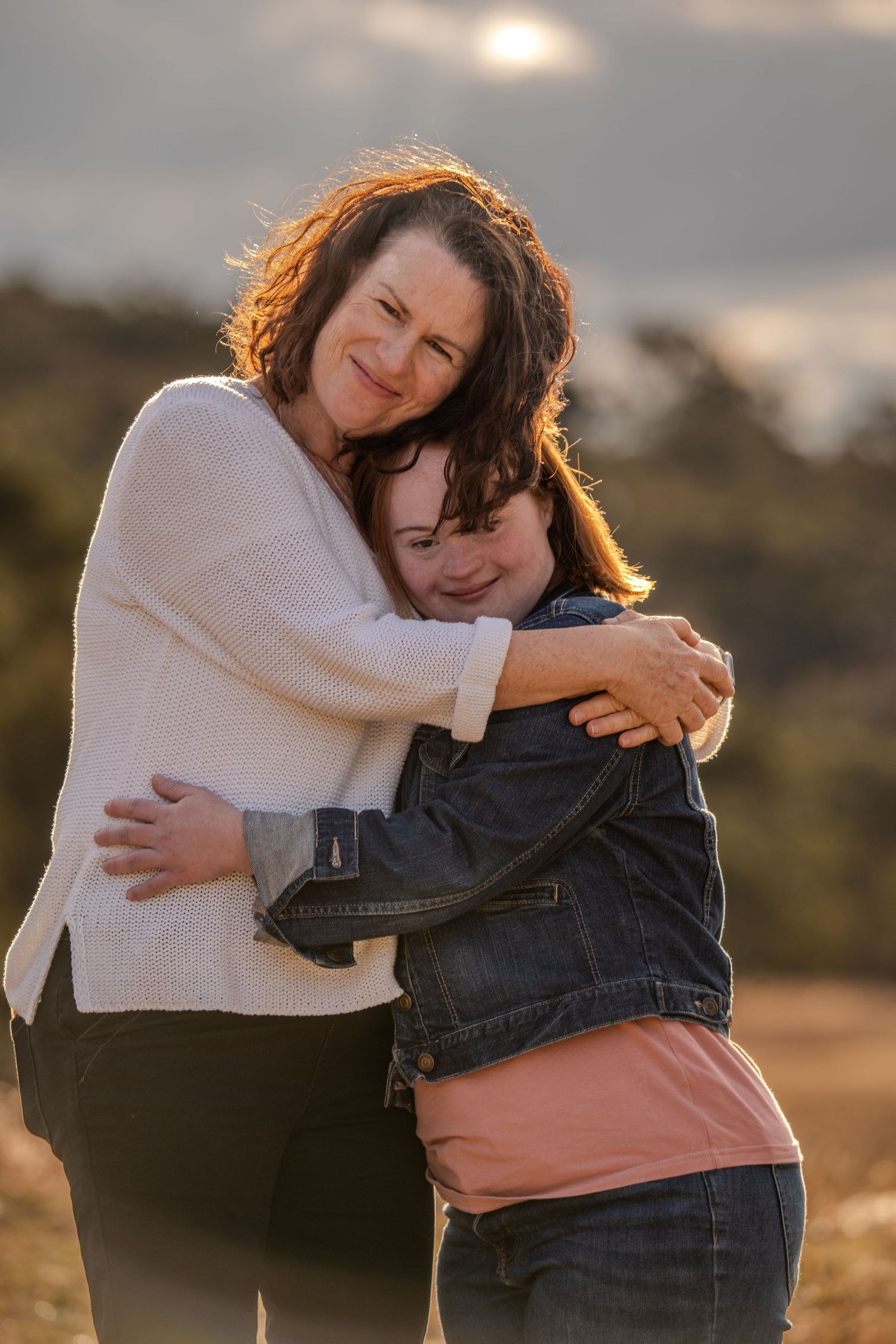 Two people sharing a warm embrace during golden hour outdoors.