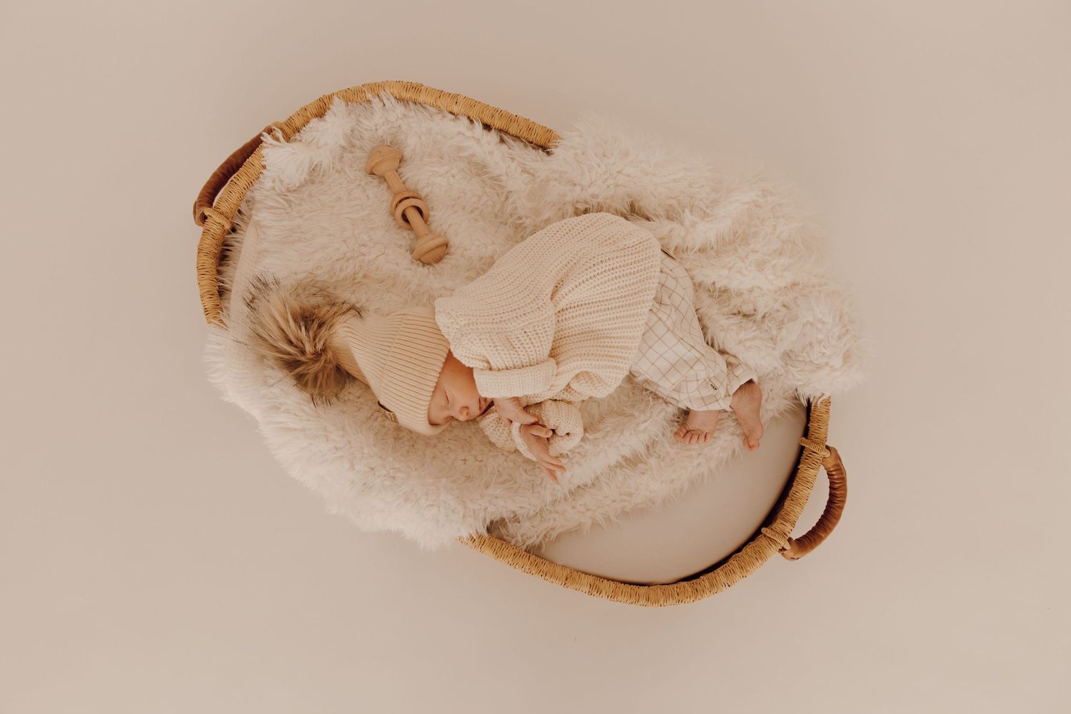 Newborn baby sleeping peacefully on a soft blanket, captured in a cozy indoor photoshoot.