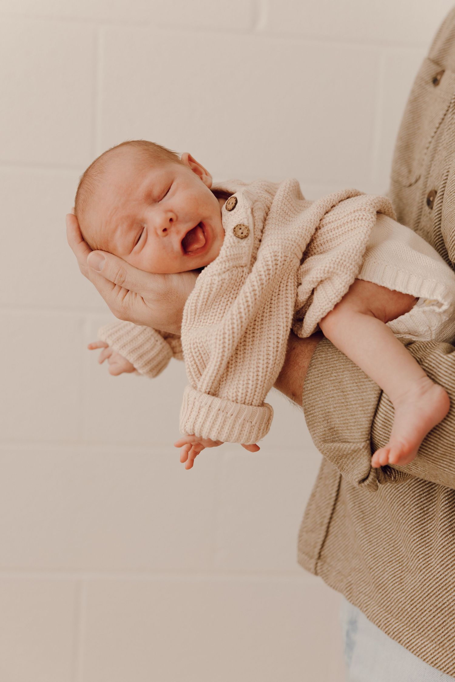 Adorable newborn portrait of a baby with closed eyes, peacefully cradled in a photographer's hands.