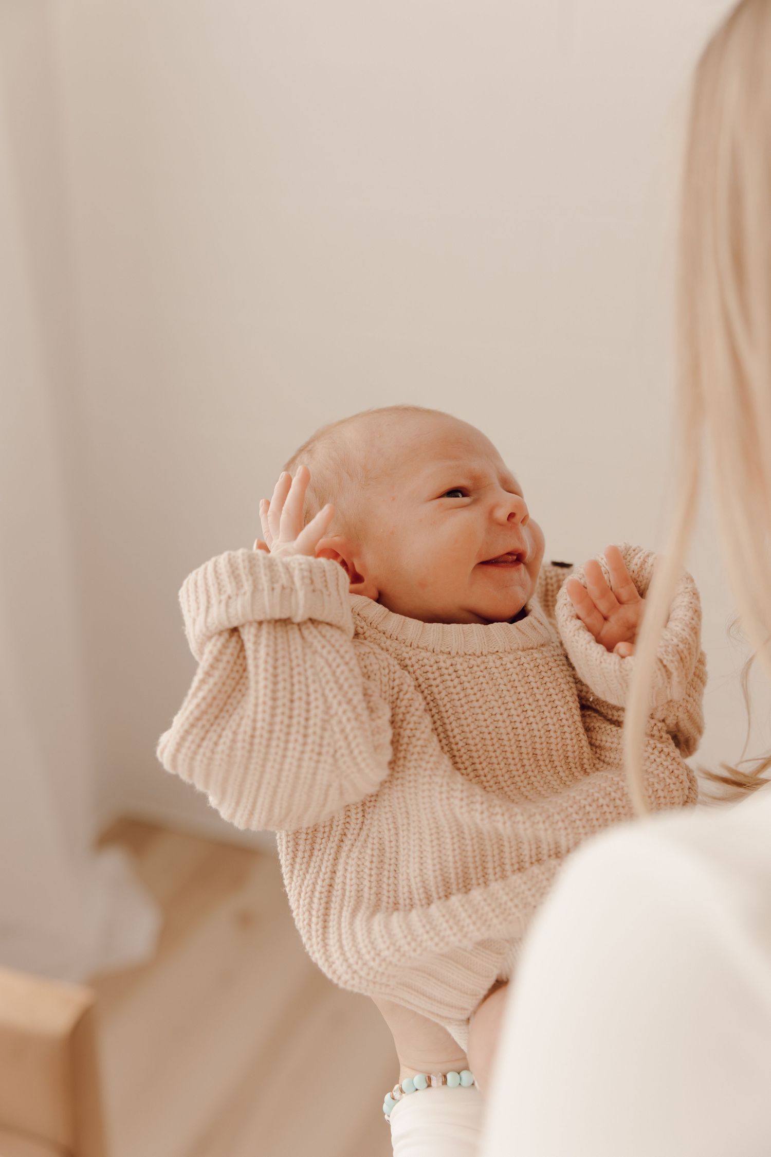 Adorable newborn portrait of a baby with closed eyes, peacefully cradled in a photographer's hands.