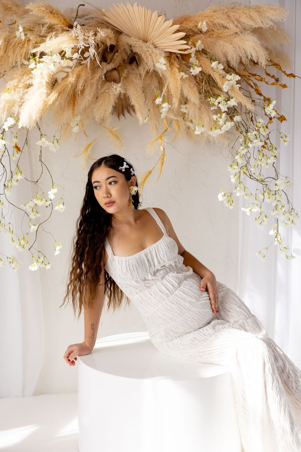 Ethereal bridal portrait with dried palm fronds and white flowers creating a romantic overhead installation.
