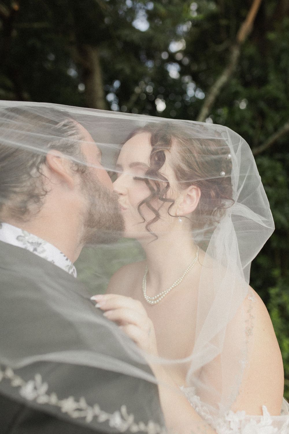 Bride and groom kissing under veil at private Morrinsville farm wedding