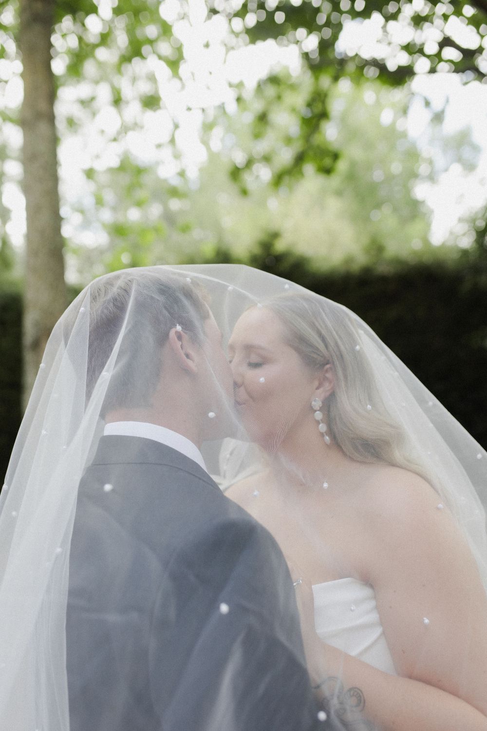 Bride and groom kissing under veil at TreeChurch and Gardens wedding