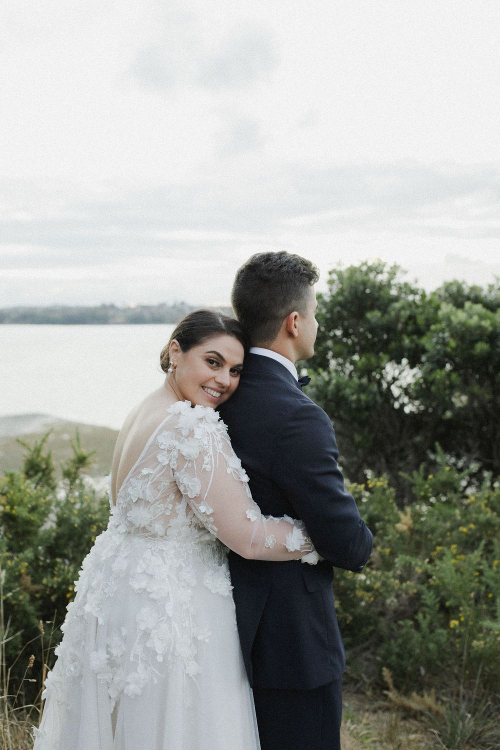 Bride hugging groom from behind at auckland wedding