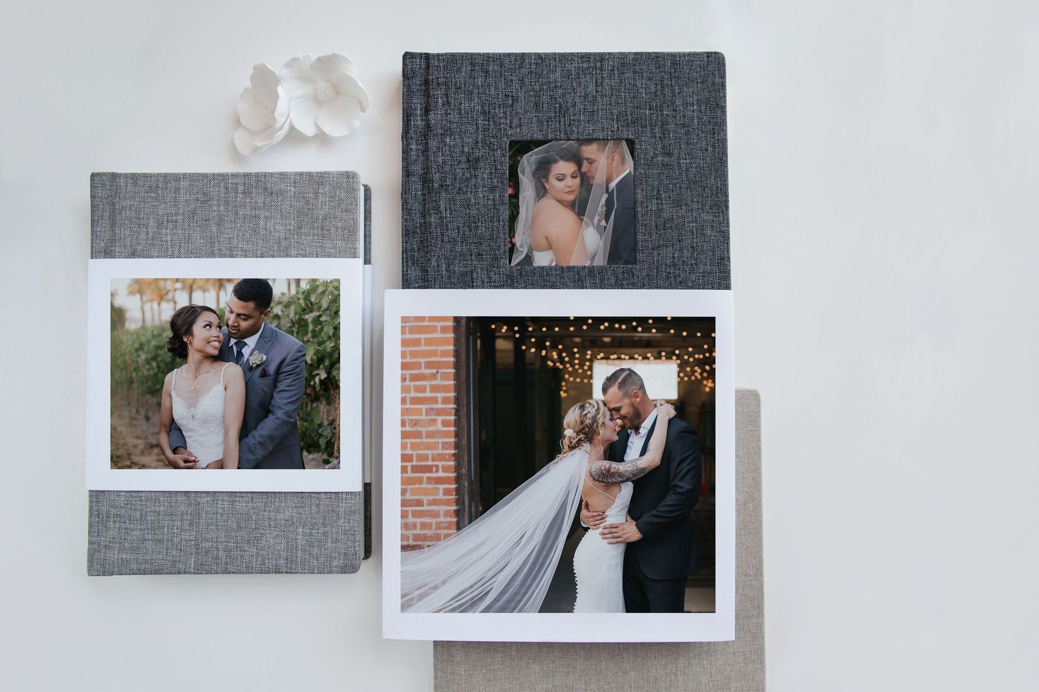 Elegant wedding albums and photo prints displayed on a textured fabric background, showcasing timeless wedding photography in albums