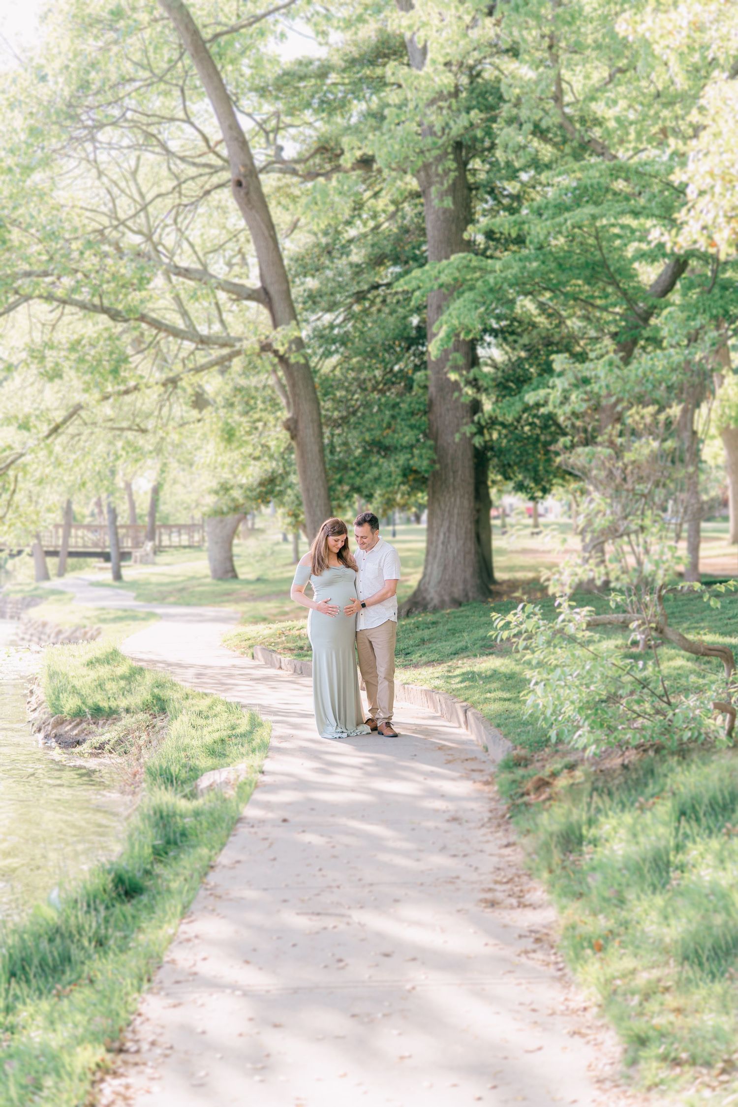 A couple embraces one another on a light colored pathway in a park in Monmouth County.