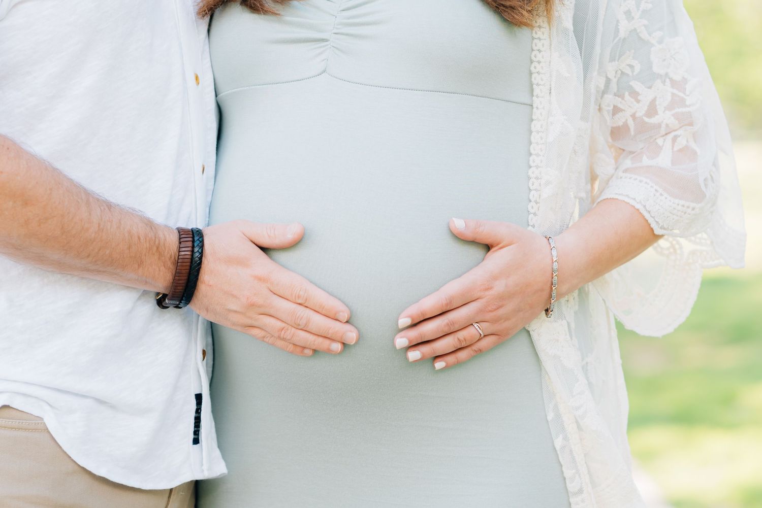 Close up of each parents hands on pregnant belly.