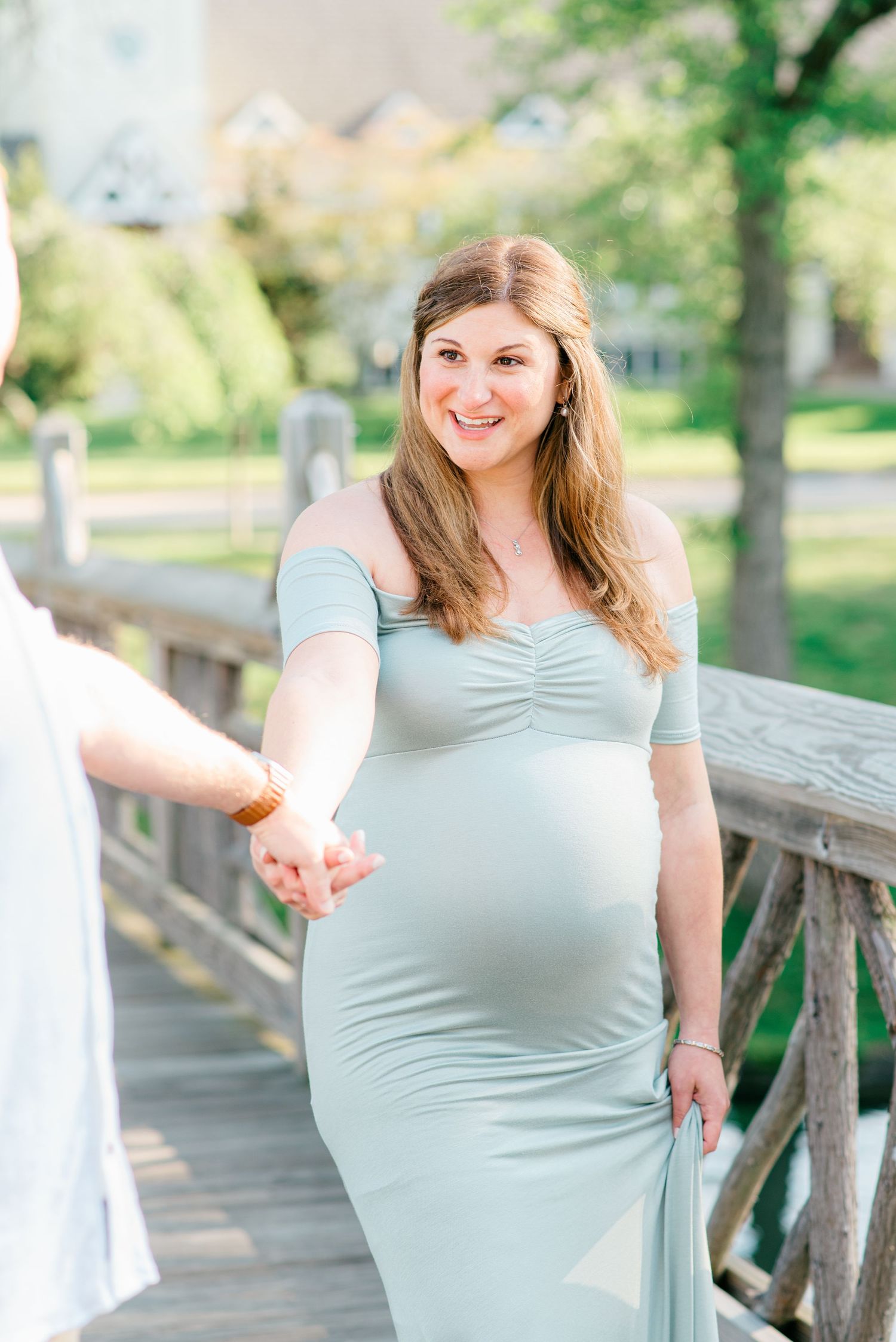 Close up of mother to be in a blue green maternity dress laughing and smiling.