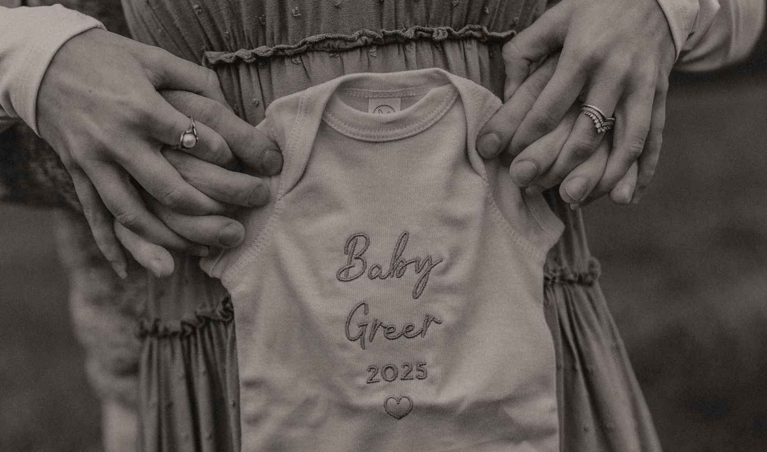 Close-up of clothing revealing 'Baby 2024' pregnancy announcement.