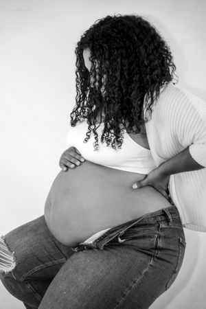 Black and white artistic maternity photo showing pregnant woman looking down at belly.