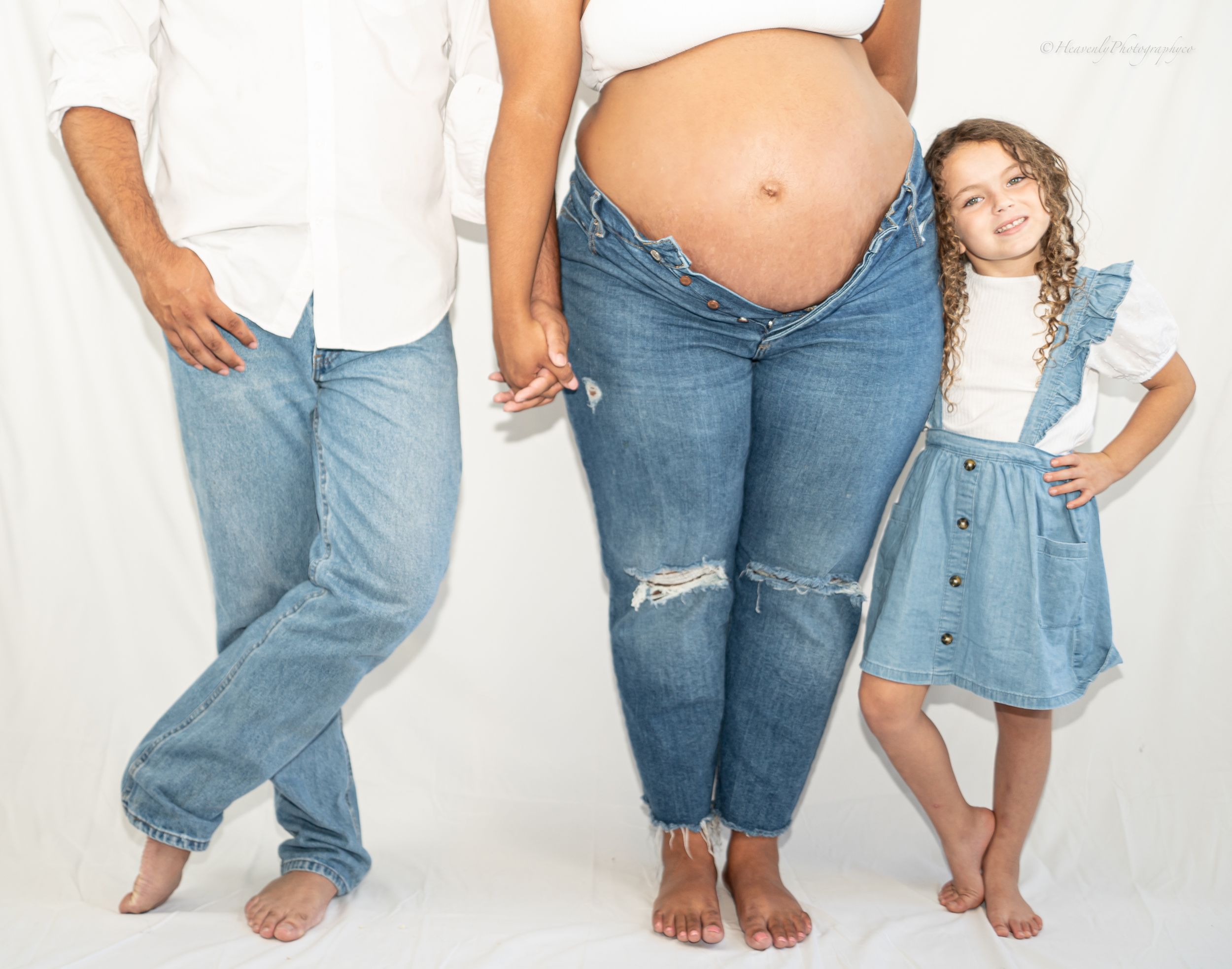 Family standing together barefoot against white background.