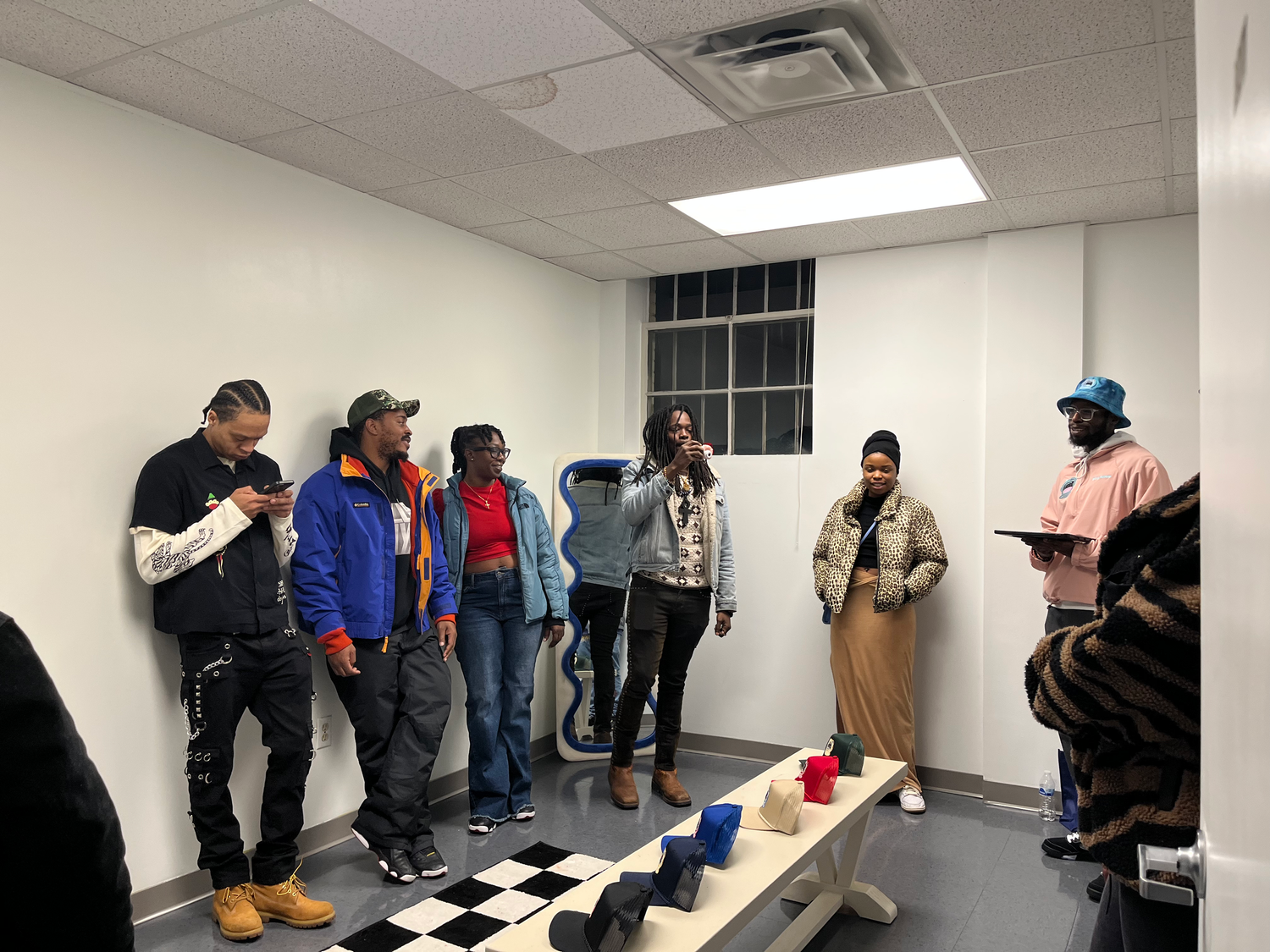 A group of people gathered in a room with black and white checkered flooring playing a drinking game.
