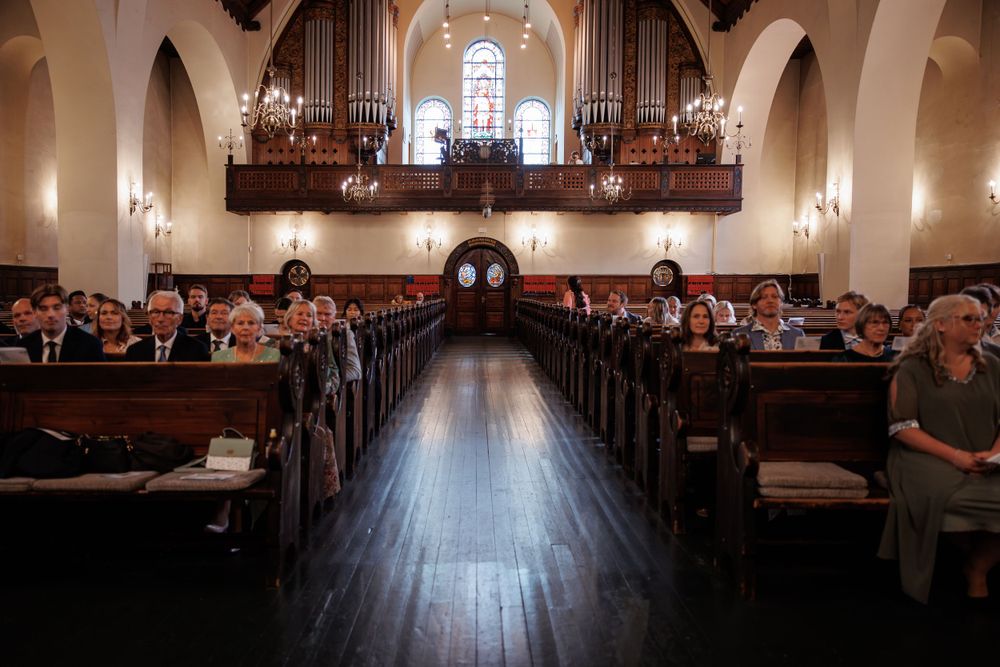 Interior view of a church sanctuary with wooden pews and an ornate pipe organ above during a church service.