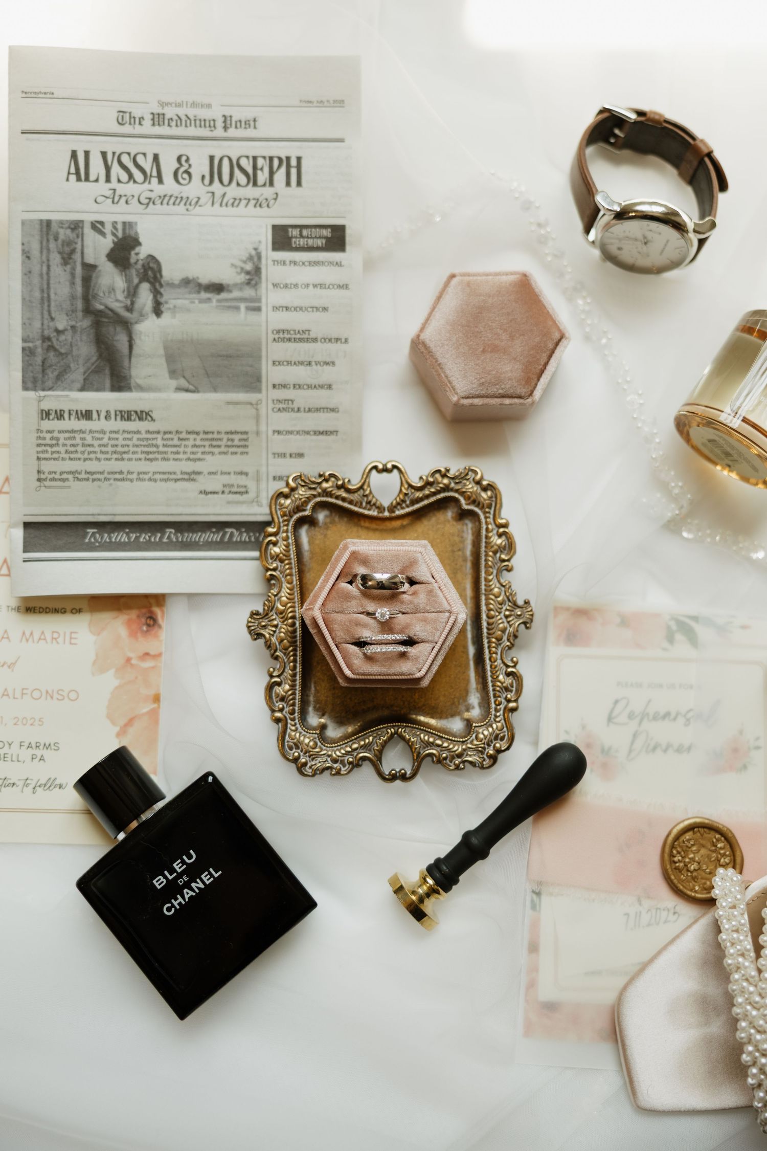 Wedding announcement details with vintage-style frame, Chanel perfume bottle, ring box and engagement details on marble surface.