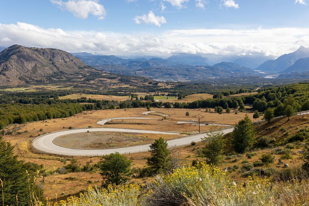 Impresionante vista de las montañas con una sinuosa carretera que atraviesa el valle, perfecta para anuncios de viajes.
