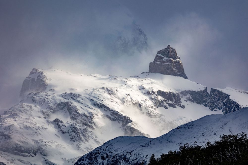 Majestuosas cumbres nevadas que atraviesan espectaculares nubes tormentosas evocando el asombro y el poderío de la grandeza de la naturaleza