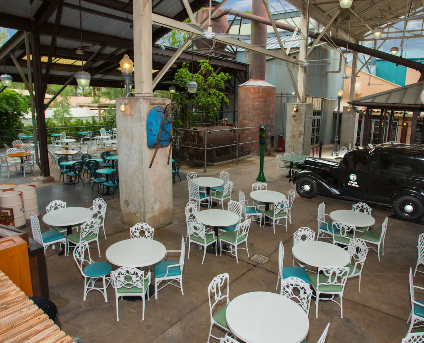 Outdoor dining area with turquoise chairs and white tables under an open-air pavilion.