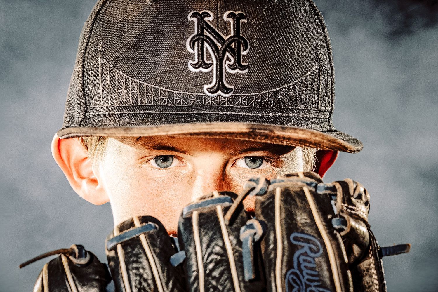 Baseball player wearing a New York Mets cap holding up a leather glove near their face with dramatic smoke background.