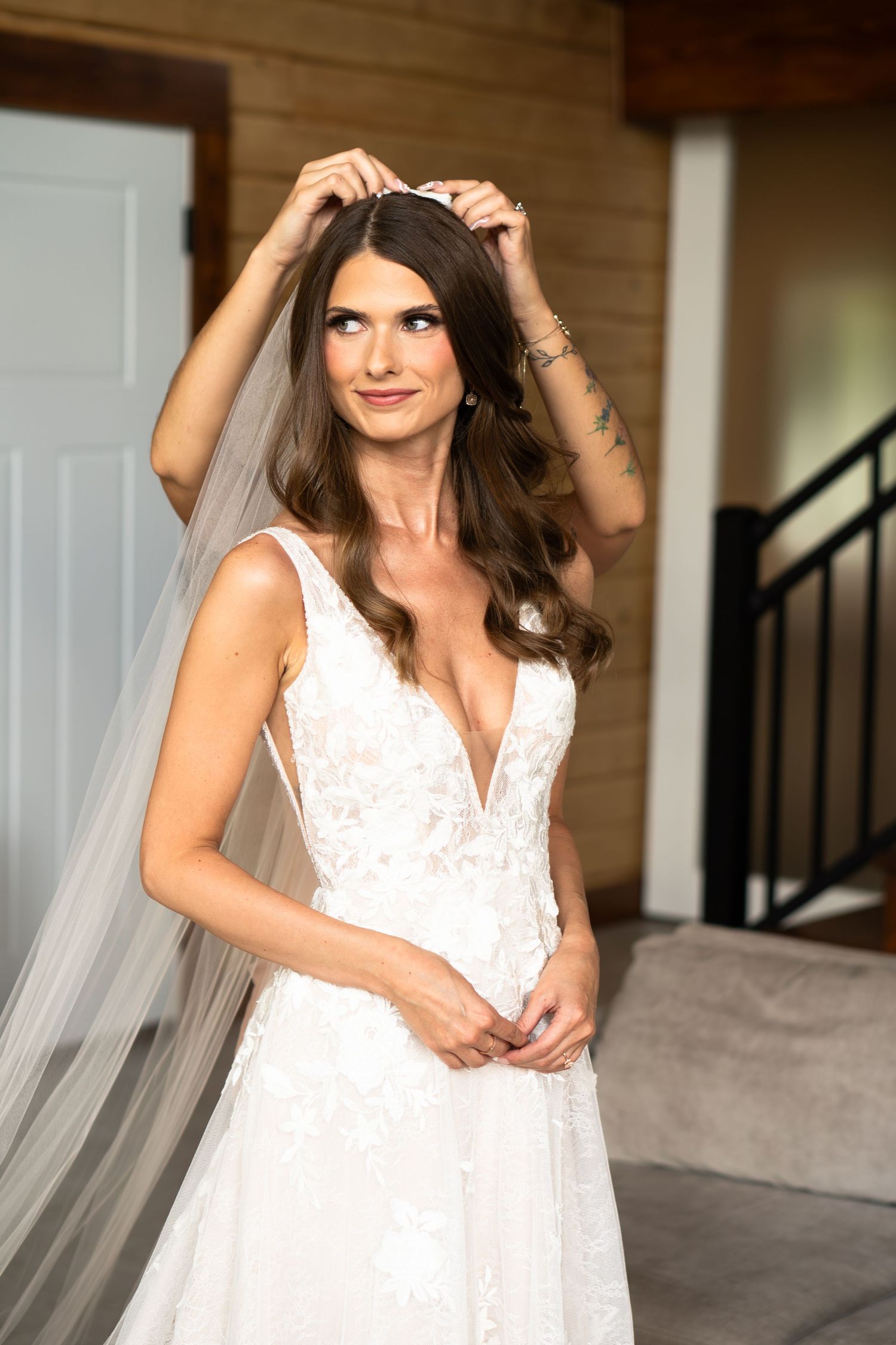 Beautiful white lace wedding gown with plunging neckline and flowing veil captured in indoor bridal portrait.
