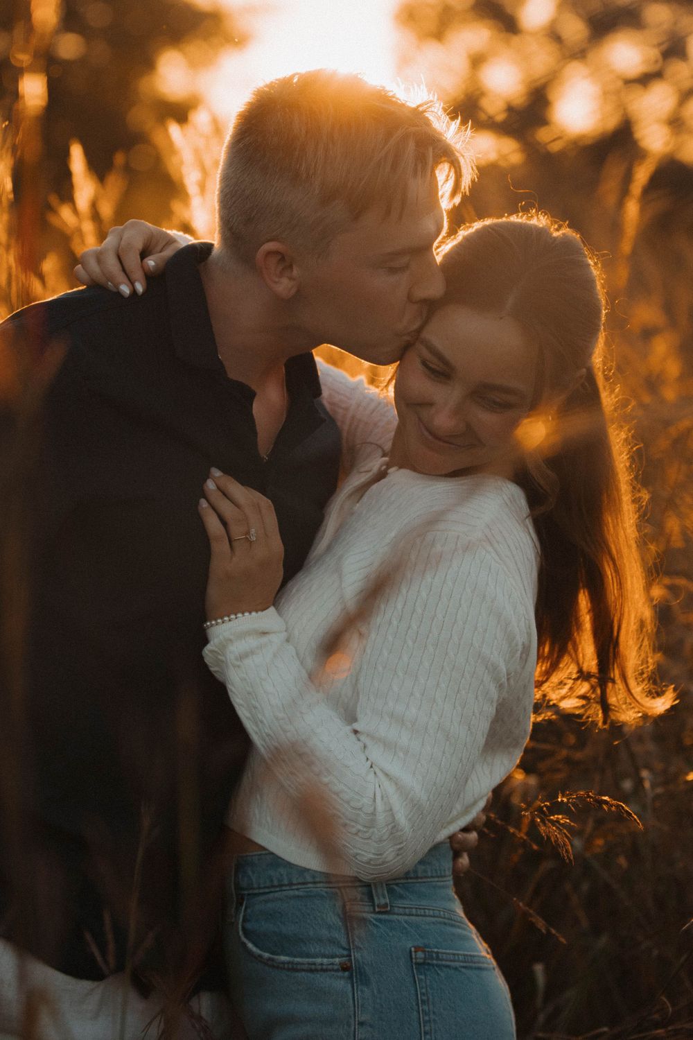A romantic sunset embrace captured with golden light filtering through trees.