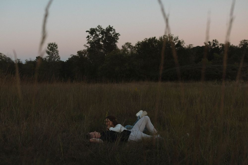 People lying in a grassy field at sunset creating a peaceful outdoor scene.