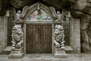 Ornate medieval stone doorway with two guardian lion statues and cherub figures adorning the gothic archway entrance.