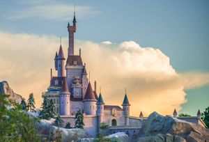 Cinderella Castle at Walt Disney World stands majestic against a dreamy blue sky with white puffy clouds.