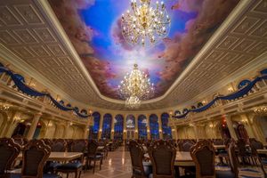 Elegant ballroom with ornate chandeliers and painted sky ceiling featuring dramatic clouds and blue arches at Disney's Be Our Guest.