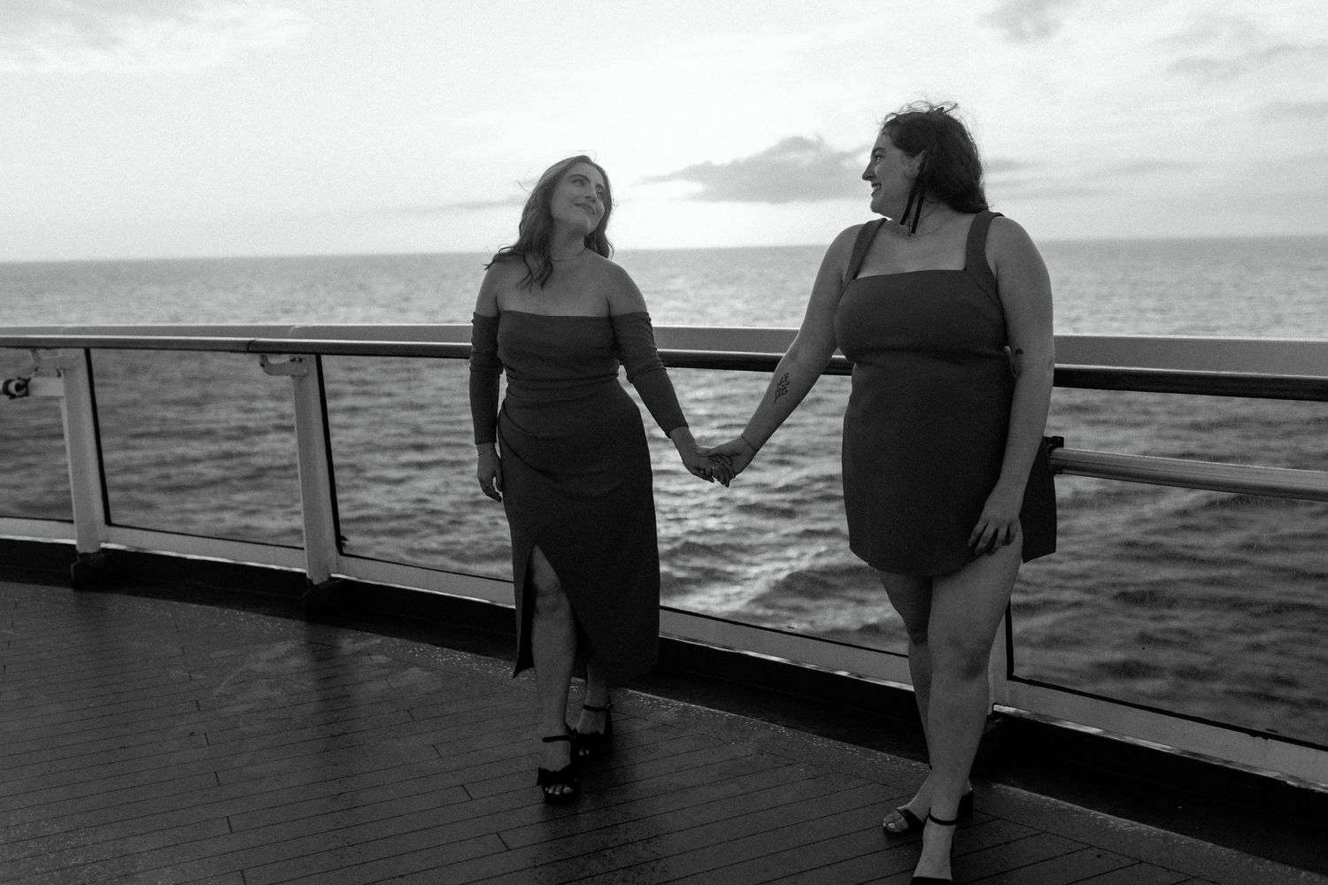 A black and white photo of two people walking hand in hand on a cruise ship deck.