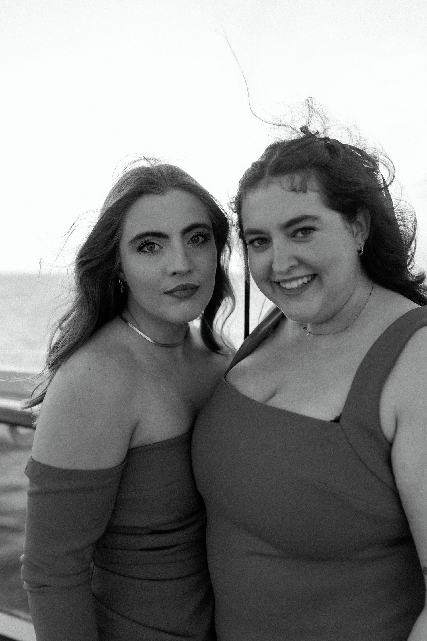 A black and white portrait of two people in matching outfits on a boat deck.