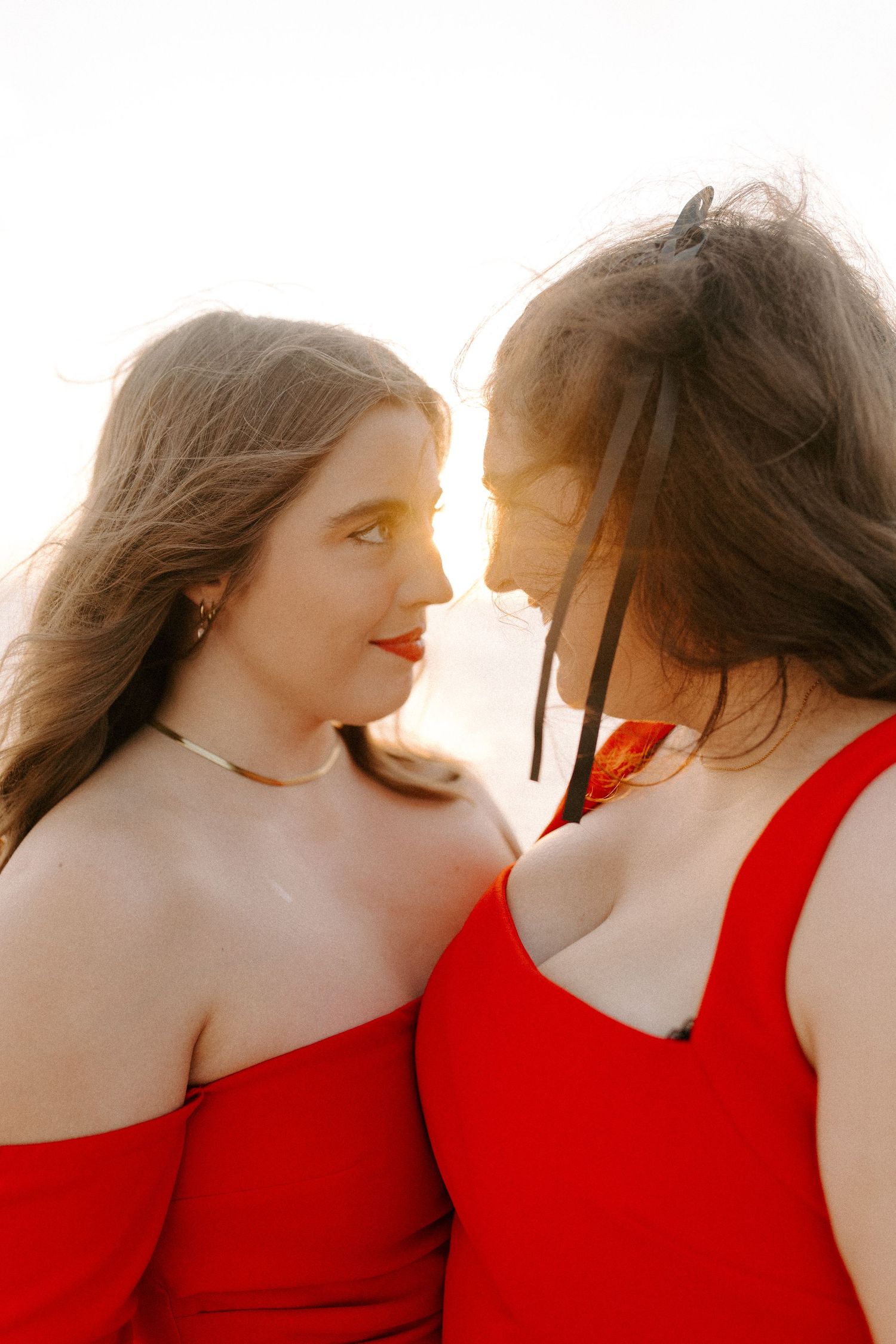 Intimate portrait of a couple in red dresses during golden hour.