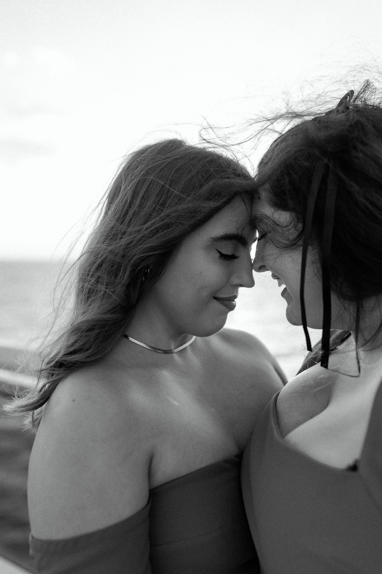 Black and white portrait of two people in formal wear sharing an intimate moment.