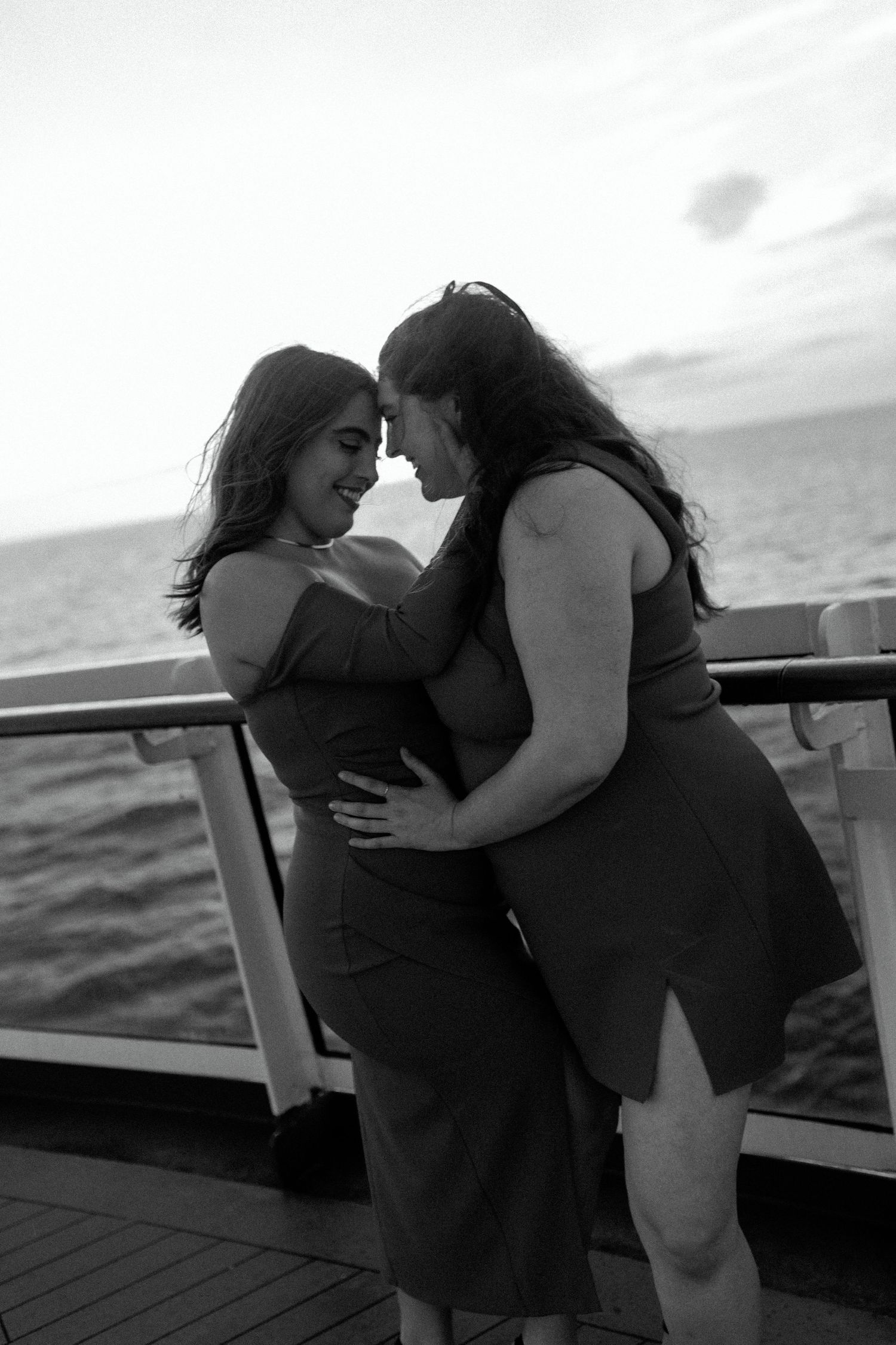 A black and white romantic portrait of two people embracing on a ship's deck.