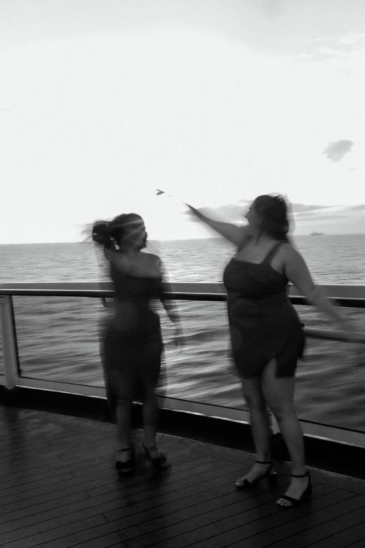 Black and white photo of two people dancing together on a ship deck at sea.