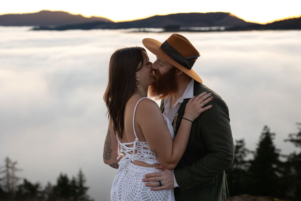 A romantic moment captured on a mountain overlook with a foggy valley below.