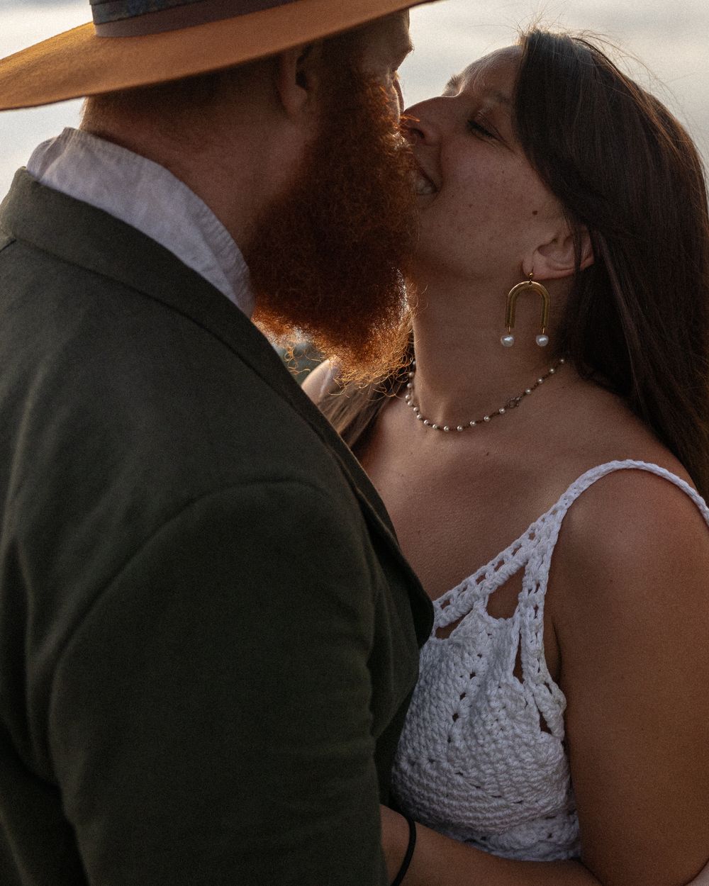 A romantic moment between a couple in formal attire at golden hour.