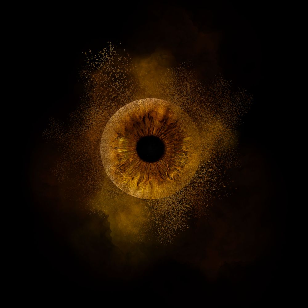 A golden-brown iris surrounded by dark background with sparkling particles creating a mystical cosmic effect.