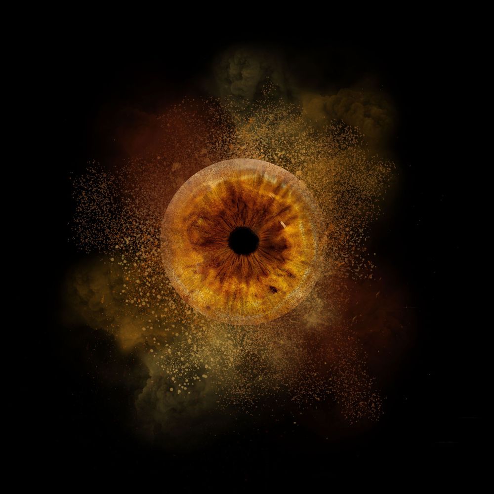 Abstract cosmic artwork shows a glowing orange eye or iris shape radiating against a dark background with golden particles.
