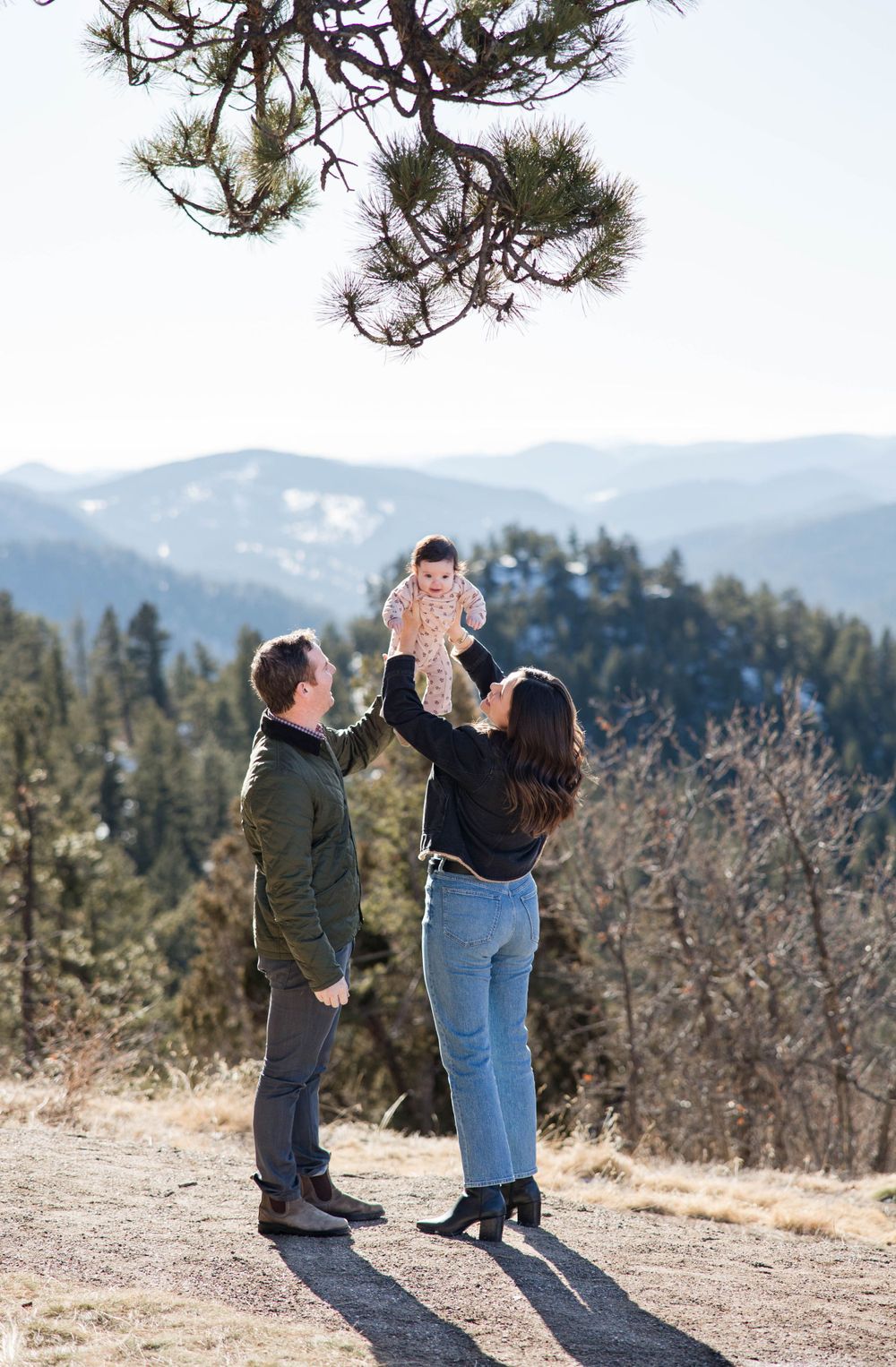 Family enjoying outdoor moment on mountain trail with scenic valley view.