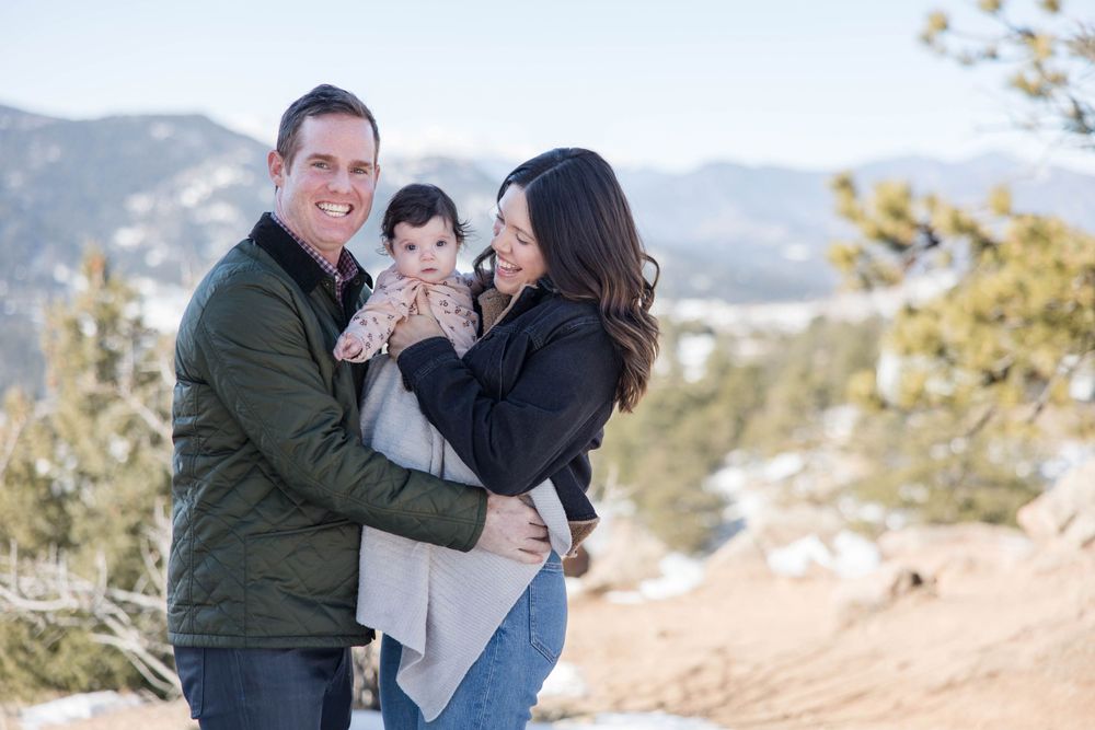 Joyful family portrait taken outdoors with mountain scenery.