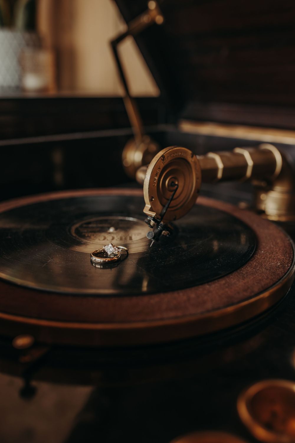 Close-up of vintage gramophone record player with tonearm and vinyl disc in warm moody lighting.