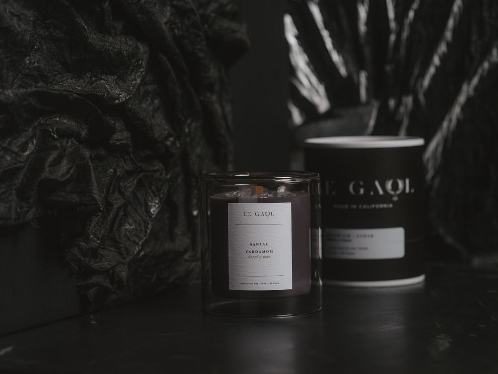 Two dark minimalist candles in glass containers with black and white labels photographed in moody lighting.