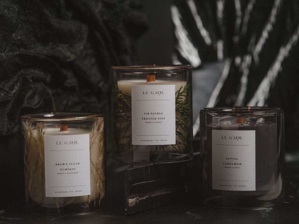 Three luxury scented candles in clear glass jars displayed against a dark textured background with dramatic lighting.