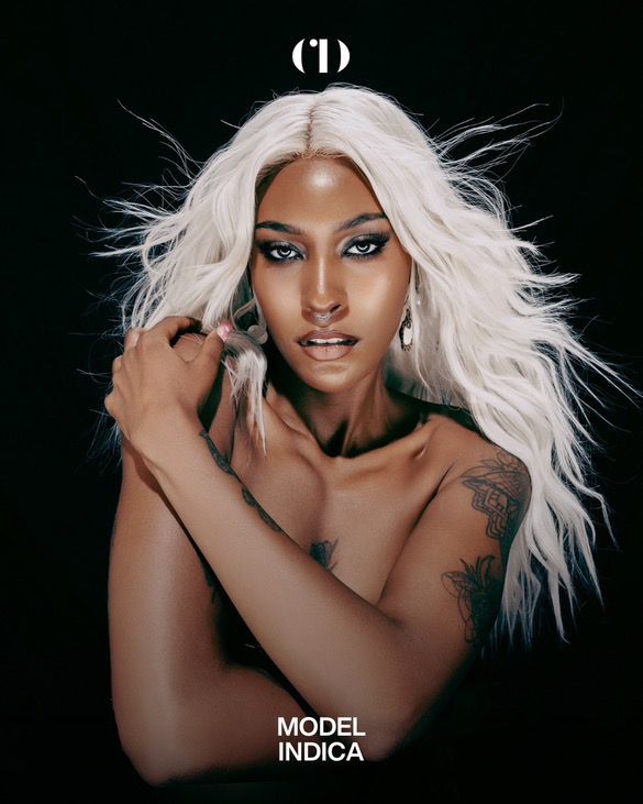 Portrait of a person with long flowing platinum blonde hair and dramatic eye makeup against a black background.