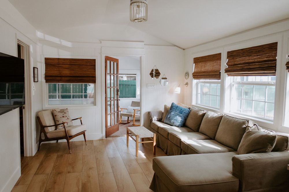 Cozy living room with wooden floors, beige sectional, and natural light from multiple windows.