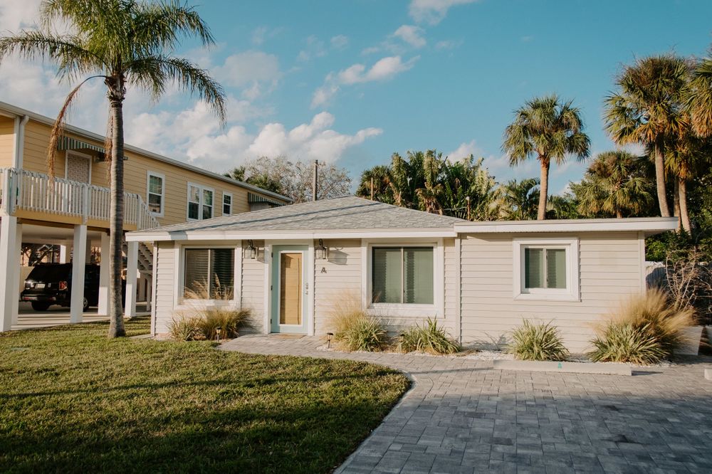 White beach house with palm trees and landscaped yard in tropical setting.