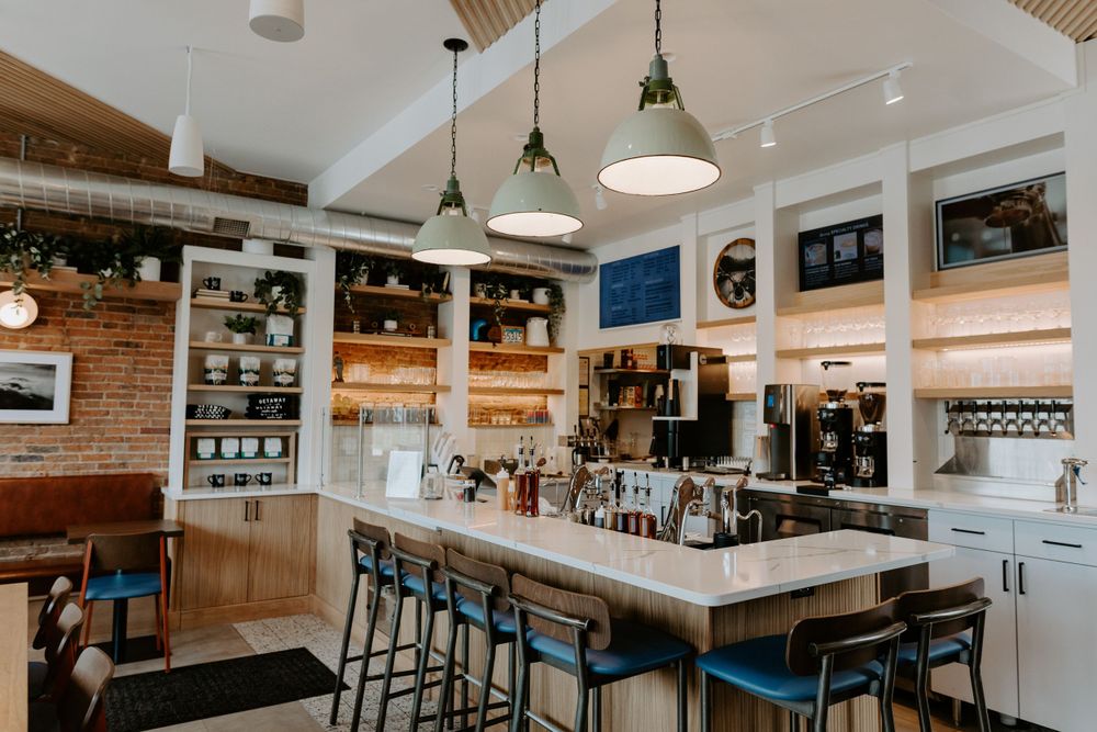 Modern industrial cafe interior with bar seating, pendant lights, and exposed brick walls.