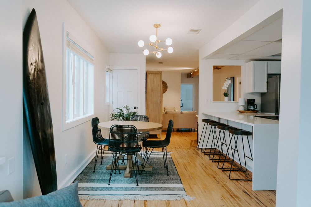 Modern open concept dining area with chandelier, round table and bar seating.