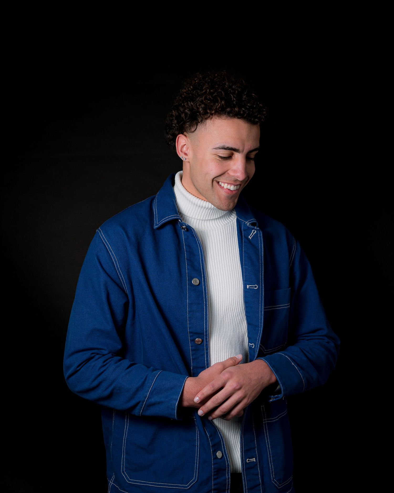 Candid portrait in blue denim jacket and white turtleneck with natural smile.
