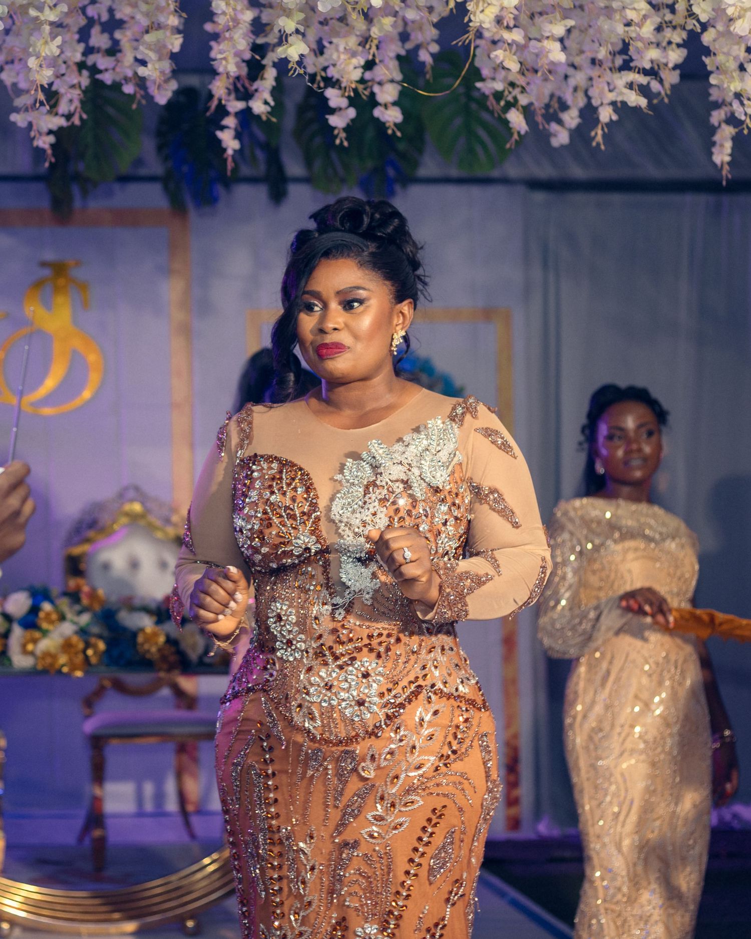 Elegant reception scene with sparkly beaded dress against purple-lit floral backdrop.